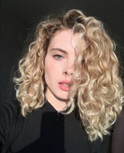 Блондована біозавивка середньої довжини, натуральний макіяж, чіткі світлотіні; стильний салонний образ.